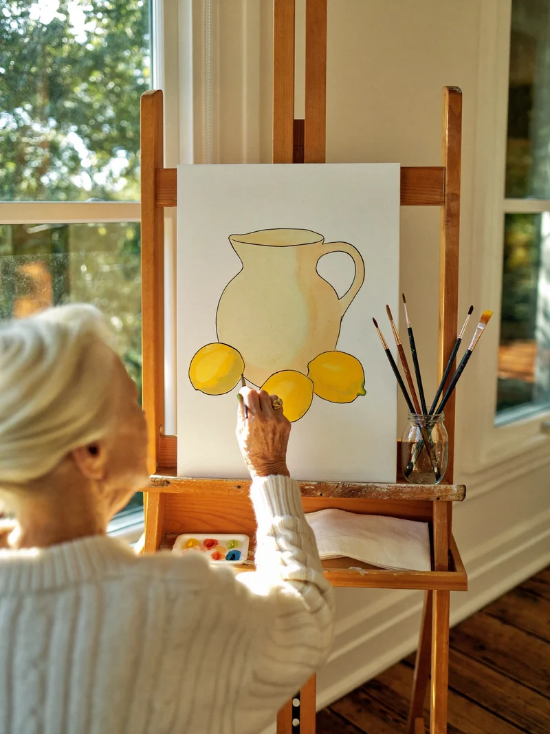 Donna anziana dipinge a acquerello una natura morta di limoni, illustrazione